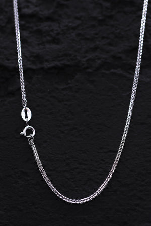 Close-up of a delicate 925 silver franco chain necklace on a textured black background. Subtle sheen, classic design.