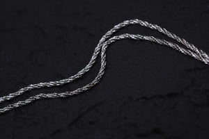 Tarnished silver chain close-up on textured black fabric. Ideal for Tibetan dzi beads or amulet necklace.
