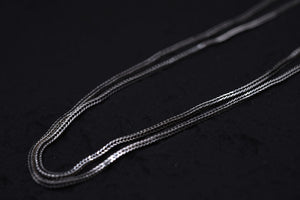 Elegant, textured silver chain close-up on black background. Simple, woven design. Tibetan prayer beads bracelet option.