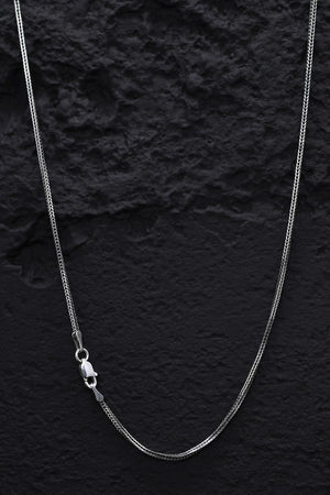 Close-up of a gleaming sterling silver snake link necklace on a black background. Classic lobster clasp.