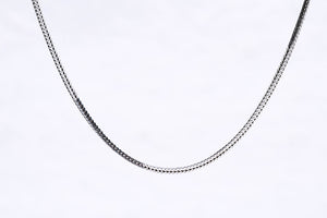 Close-up of a minimalist silver chain necklace on white. Delicate, textured weave adds subtle elegance. Ideal for layering or everyday wear.