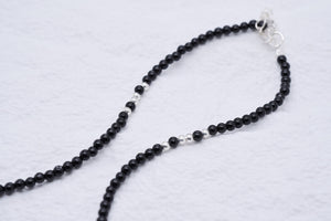 Elegant black and silver beaded necklace on white. Tibetan dzi beads create subtle contrast. Simple, stylish.