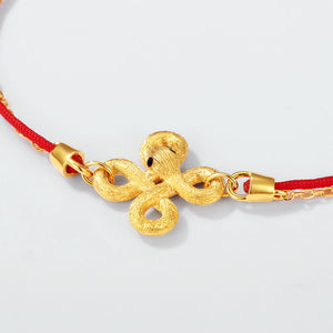 Elegant gold endless knot charm bracelet on red string. Tibetan Buddhist prayer beads with minimalist design.