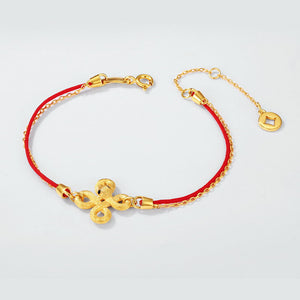 Red string bracelet with gold Chinese knot charm and extender chain. Minimalist Buddhist prayer beads jewelry on off-white background.