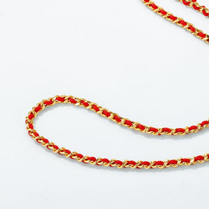 Close-up of a gold and red Tibetan rope-like chain on a white background. Intricate detail, minimalist style.