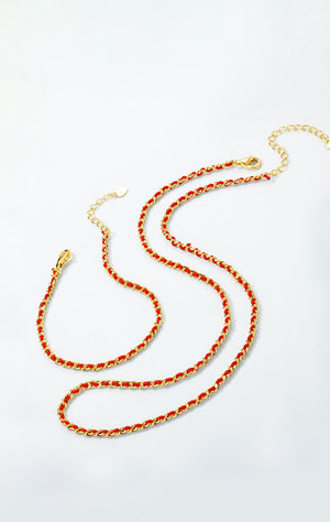 Two intertwined gold chain necklaces with red cord on white. Minimalist, vintage style with tiny heart charms. Buddhist prayer beads.