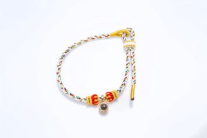 Braided cord bracelet with red beads and gold accents. Features a central locket and adjustable closure.