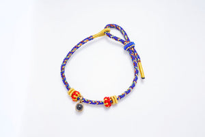 Braided cord bracelet with gold accents, adjustable sliding knot, and colorful design.