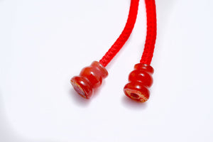Red string bracelet with two carved carnelian dzi beads. Simple, minimalist style. Tibetan Buddhist prayer beads.