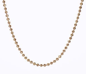 Close-up of a delicate gold moon-cut bead chain necklace on white. Tibetan dzi beads create a symmetrical design.