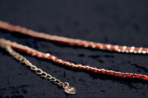 Gold chain bracelet with interwoven red thread and engraved heart charm. Tibetan Buddhist prayer beads for mindful style.
