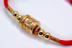 Red string bracelet with gold Tibetan dzi bead, accented with smaller gold beads and metallic thread. Simple, elegant style.