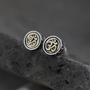 Silver Om stud earrings with textured, beaded borders on dark stone. Simple, spiritual Tibetan Buddhist style.