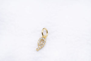 Gold number 9 charm with diamonds on a white textured background. A sparkling, lucky number pendant.