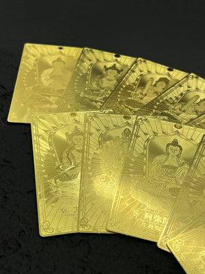 Close-up of gold Tibetan dzi beads fanned out, showcasing embossed Buddha figures and intricate patterns.