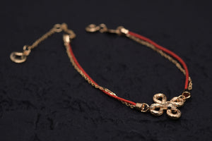 Elegant gold & red Tibetan dzi bead bracelet on dark background. Minimalist style, featuring a quatrefoil charm and delicate gold chain accent.