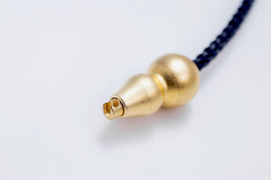 Gold gourd-shaped Tibetan dzi bead pendant on a dark braided cord. Simple, elegant, and perfect for spiritual jewelry.