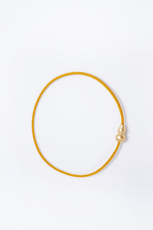 Elegant minimalist gold cord bracelet on white background. Features a unique gourd-shaped clasp. Tibetan Buddhist inspired jewelry.