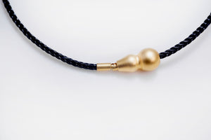 Elegant minimalist necklace featuring a braided black cord and small, gold, gourd-shaped clasp. Tibetan dzi beads style.