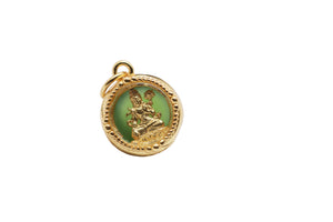 Gold pendant featuring a green stone with a golden deity figurine. Intricately designed with beaded pattern and loop for attachment.