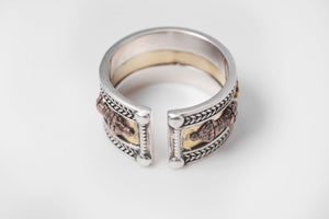 Adjustable silver and brass Tibetan ring on white background. Features copper dragon symbols on gold band with braided silver detail.