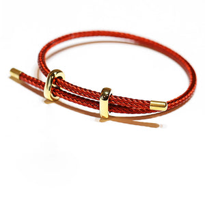 Red woven bracelet with gold accents. Adjustable closure, minimalist design, vibrant color.