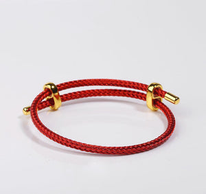 Red braided bracelet with gold accents. Stylish and durable wrist accessory.