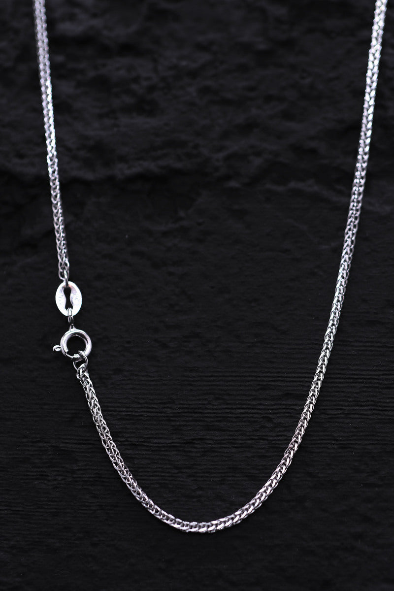 Close-up of a delicate 925 silver franco chain necklace on a textured black background. Subtle sheen, classic design.