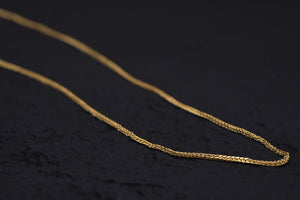 Close-up of delicate, textured gold chain on black background. Ideal for Tibetan dzi beads or amulet necklace.