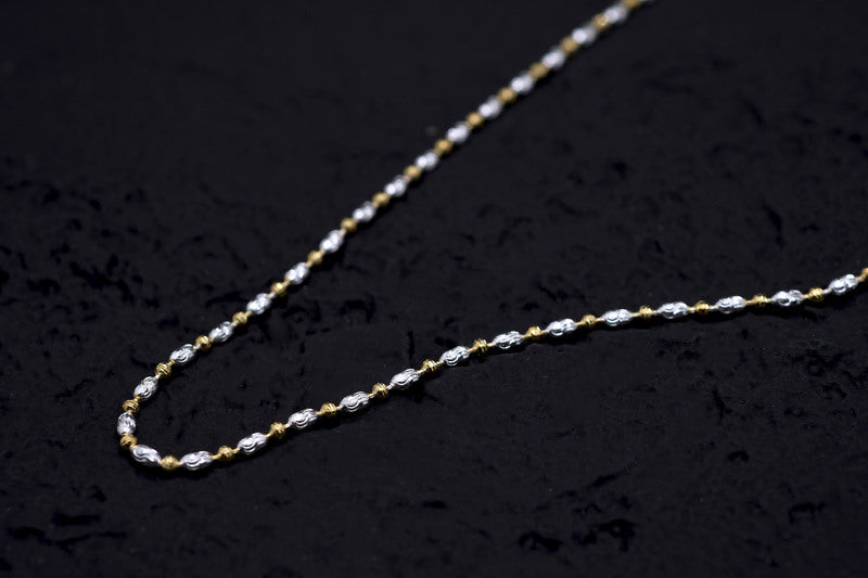 Close-up of a delicate gold & silver chain necklace on black. Intricate oval links highlight the two-tone design. Amulet necklace.