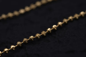 Close-up of delicate gold Tibetan dzi beads on a black textured background. Elegant and simple style.