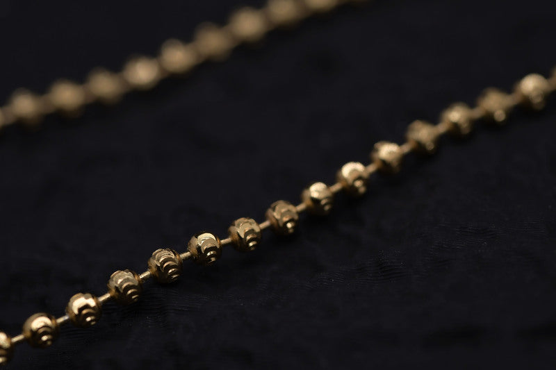 Close-up of delicate gold Tibetan dzi beads on a black textured background. Elegant and simple style.