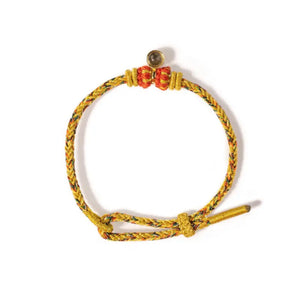 Braided bracelet with yellow, red, green, and black cords, knot closure, and bell with dark stone. Bohemian style bracelet on white.
