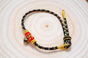 Woven cord bracelet close-up on wood. Adjustable friendship bracelet with gold beads and sliding knot closure.