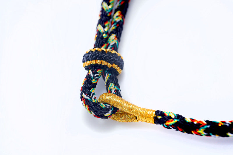 Braided decorative cord with colorful threads & golden knot detail.