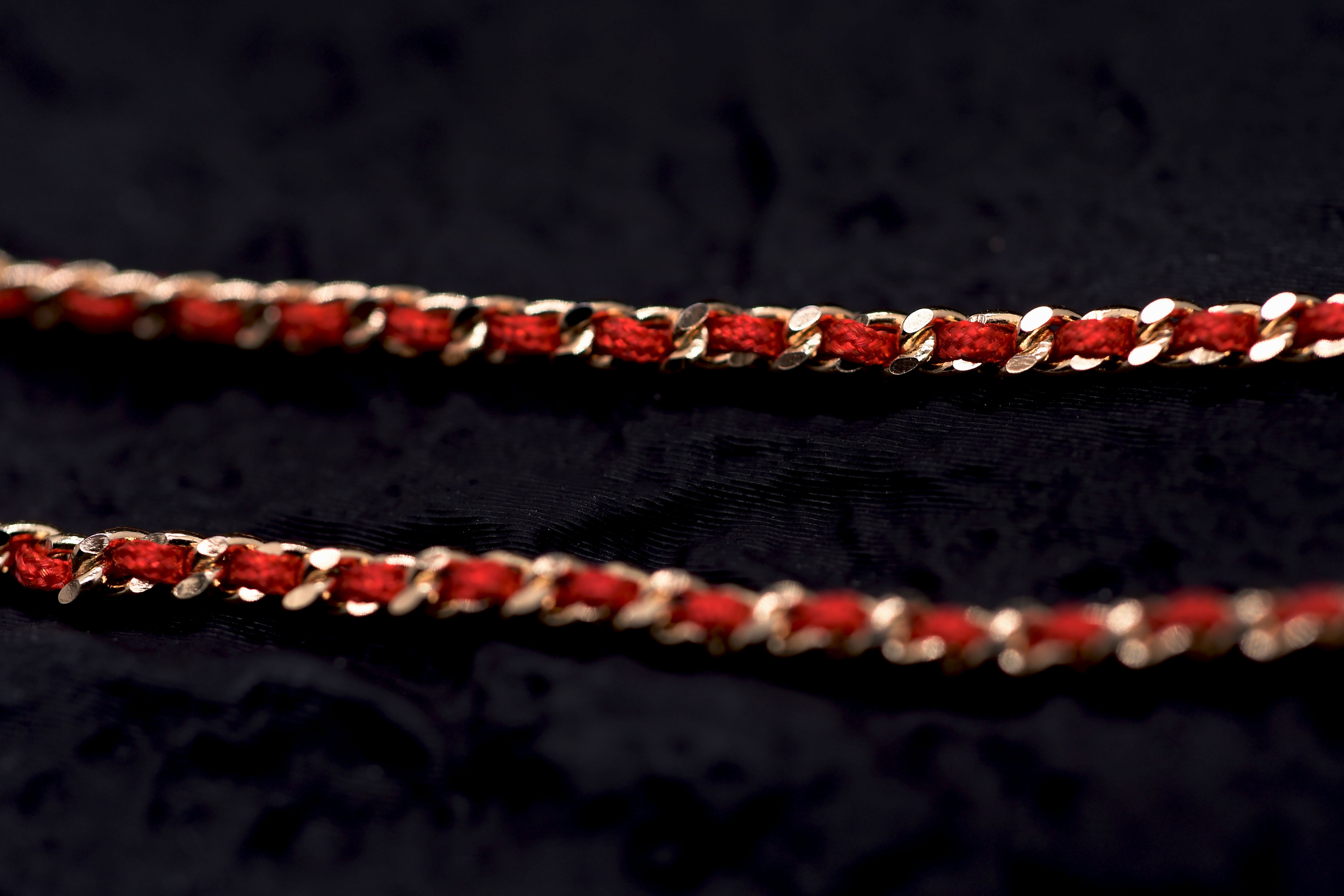 Gold chain with red thread accents on dark background. Elegant Tibetan Buddhist prayer beads.