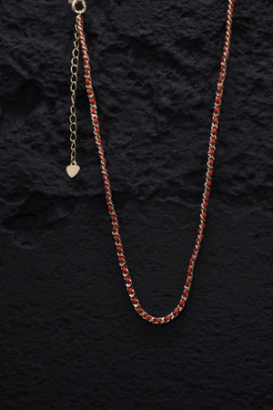 Elegant gold chain necklace with red thread accent and heart charm on black background. Tibetan Buddhist prayer beads style.