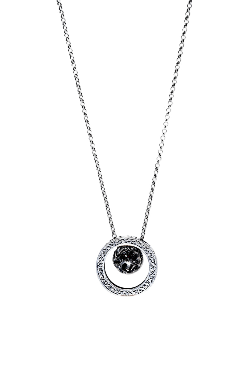 Close-up of an elegant Tibetan dzi bead necklace. Delicate silver chain with ornate pendant framing a textured dark silver sphere, promoting wealth & luck.