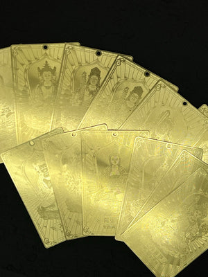 Close-up of gold Tibetan plaques with etched Buddhist deities, lotus flowers, and Chinese characters. Ideal for thangka art enthusiasts.