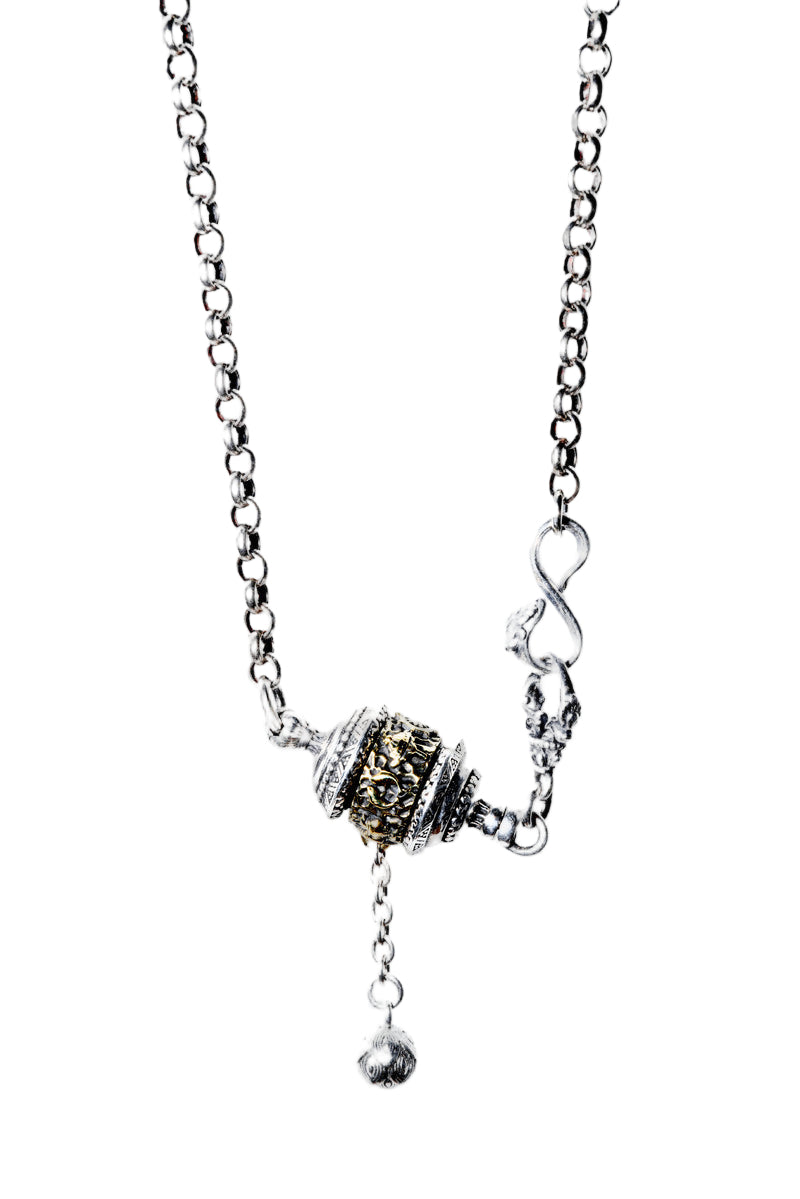 Sterling silver Tibetan prayer wheel necklace pendant on white background. Intricate metalwork with gold accents. Bohemian style.