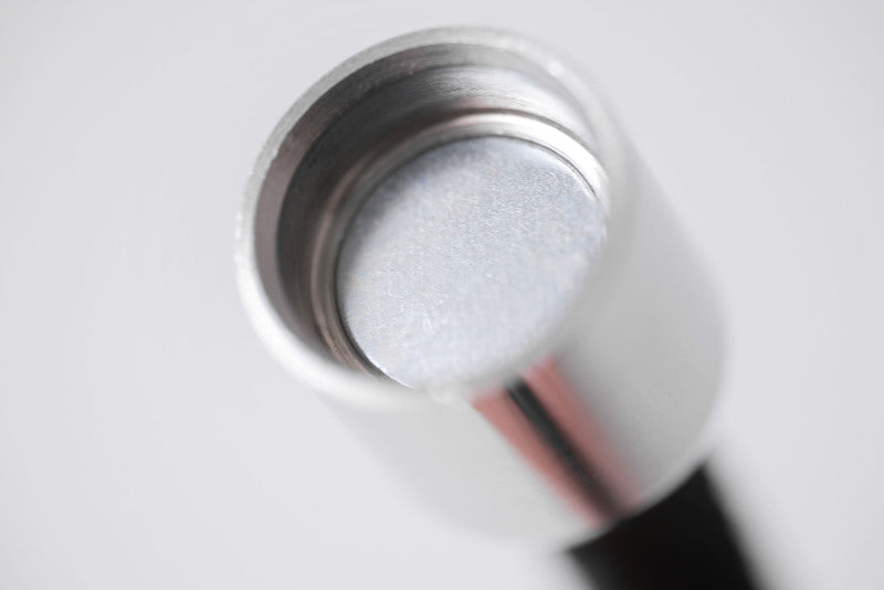 Close-up of a metallic Tibetan dzi bead with textured gray center. Macro photography showcases intricate details.