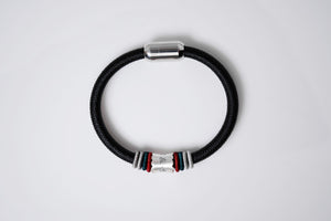 Close-up of a stylish men's black braided bracelet with Tibetan dzi bead details, silver clasp, and minimalist design.