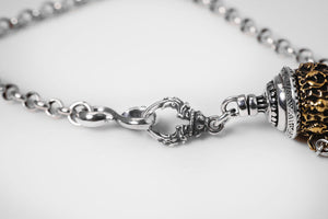 Intricate silver and gold necklace with textured conical pendant and ornate clasp. Tibetan dzi beads inspire this fine jewelry piece.