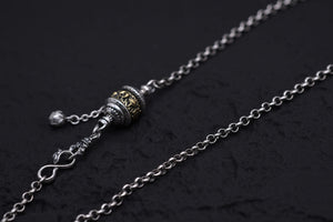 Elegant silver necklace with two-tone pendant featuring gold detailing against a dark engraved metal. Tibetan dzi beads inspire this simple, stylish piece.