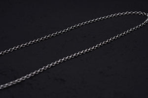 Delicate silver chain gleaming against a dark background. Minimalist, elegant jewelry for layering with Tibetan dzi beads or a protective amulet.