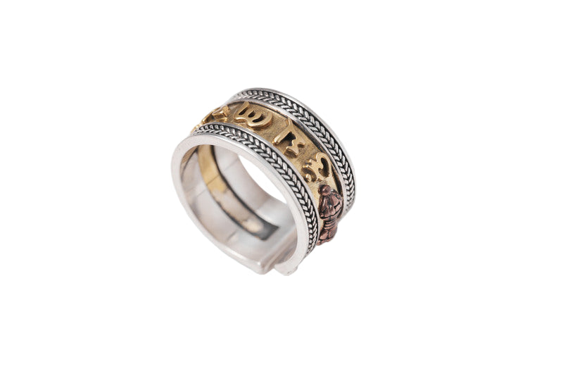 Close-up of a Tibetan ring with braided silver band, gold mantra inscription, and copper charm. This adjustable ring offers wisdom and protection.