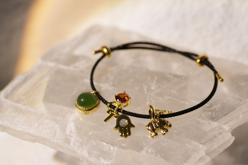 Black cord bracelet with jade, orange gemstone, key, Hamsa, elephant charms.