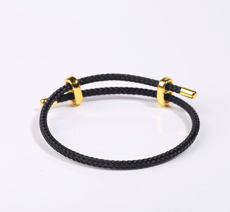 Black braided bracelet with gold accents and adjustable beads.