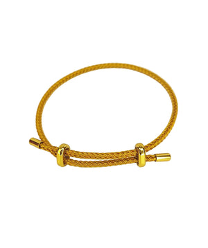 Close-up of an adjustable gold braided bracelet with sliding rings and cylindrical tip on a white background.